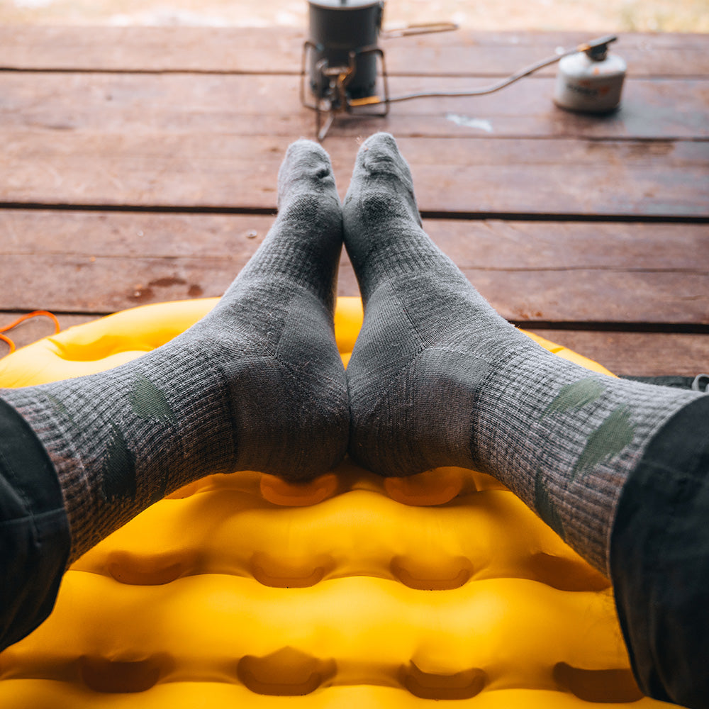 Forest merino crew socks resting on a wooden camp deck