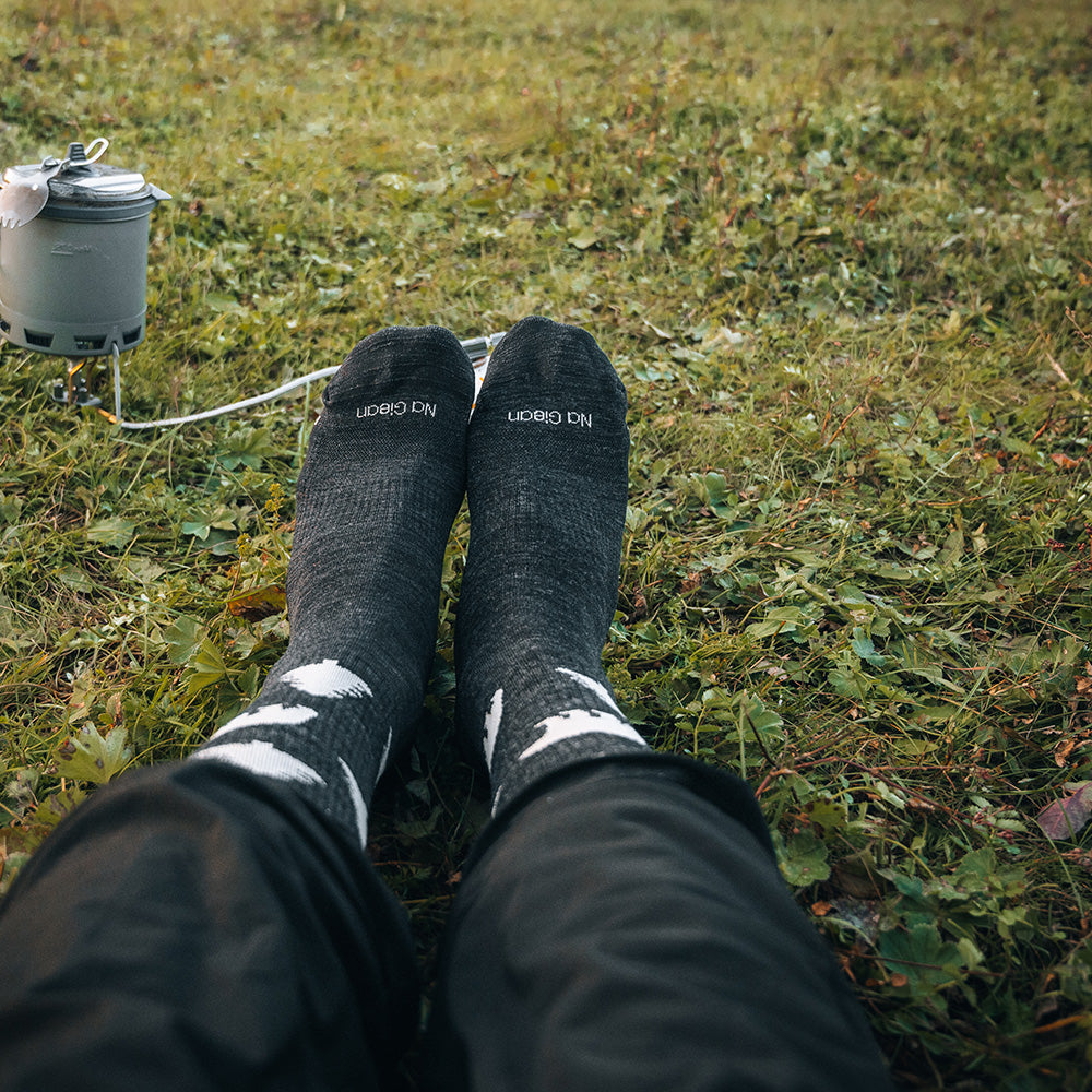 Jungle merino crew socks at a grassy campsite beside a portable stove