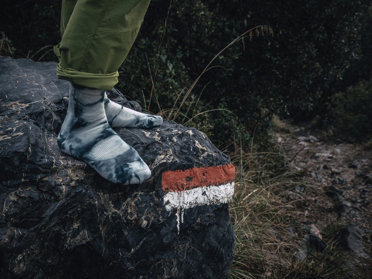 Hiker standing on a rock in tie-dye merino wool crew hiking socks